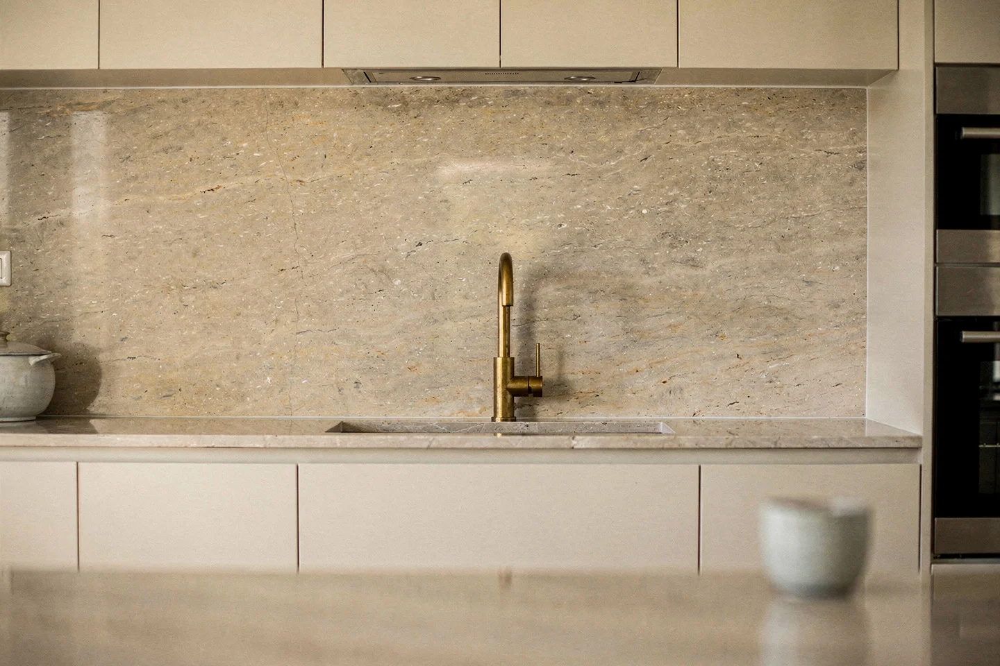 Full-height honed stone splashback in single slab behind the cooking run